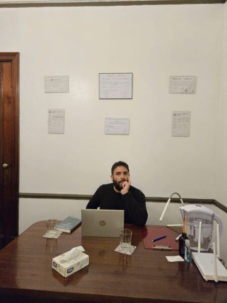 Terapeuta con la mano en la cara (pensando) Terapeuta en su consultorio con la mano en el menton reflexionando