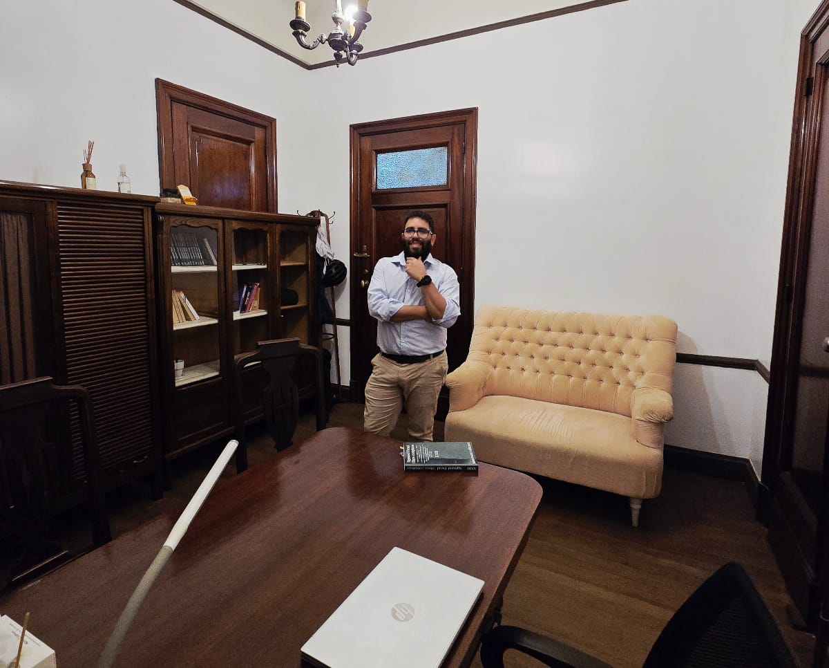 Terapeuta en el centro del consultorio pensando Terapeuta en consultorio de pie, reflexionando